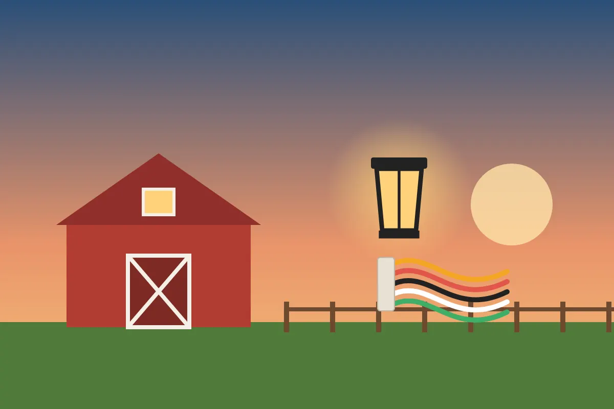 Red barn at sunset with a lit lantern and electrical cable along a fence