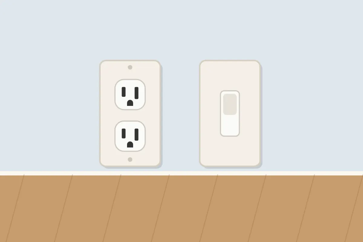 White duplex outlet and a light switch on a pale blue wall above a wood floor